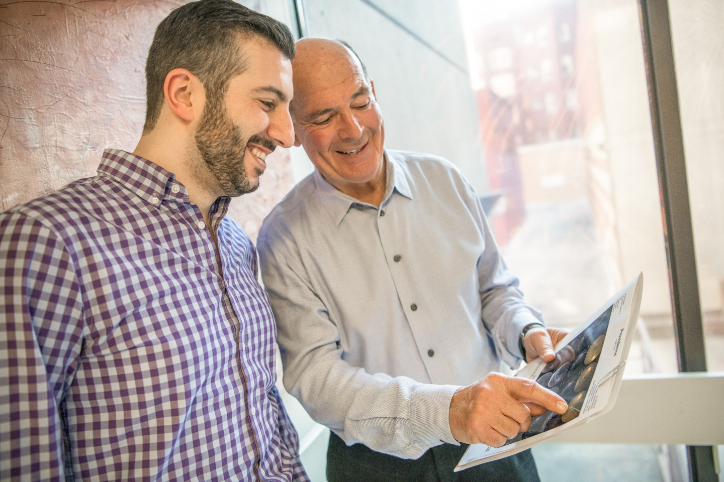 Dr. William Ross and retina fellow Dr. Nakhoul look at a document, smiling.
